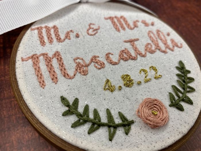 Hand-embroidered wedding hoop reading Mr. & Mrs. Moscatelli 4.8.22 with a rose and leaves