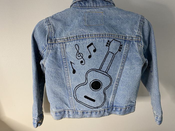 Back of a denim jacket embroidered with a guitar and music notes