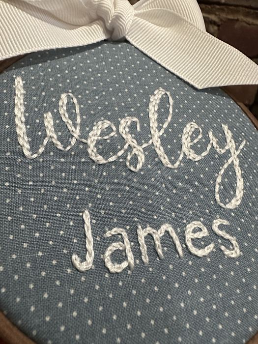 Close-up of Wesley James embroidered in white on a blue hoop
