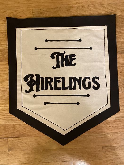 Black and white banner embroidered with The Hirelings