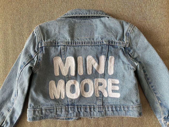 Back of a kids denim jacket with MINI MOORE in white chainstitch