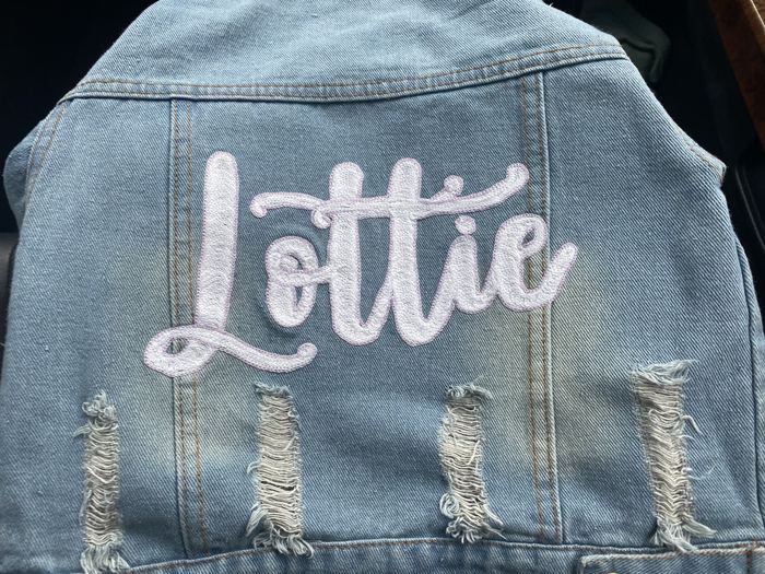 Back of a cropped denim jacket with Lottie in white chainstitch