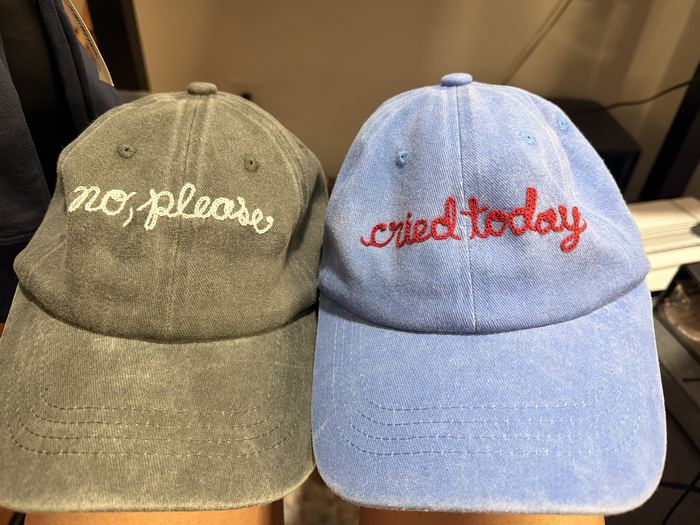 Two baseball caps embroidered with no, please and cried today