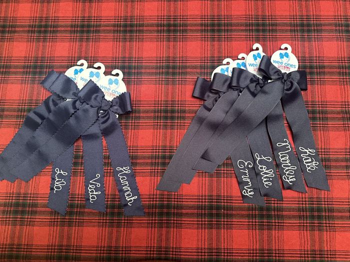 Navy hair bows with names embroidered in white chainstitch on the ribbon tails