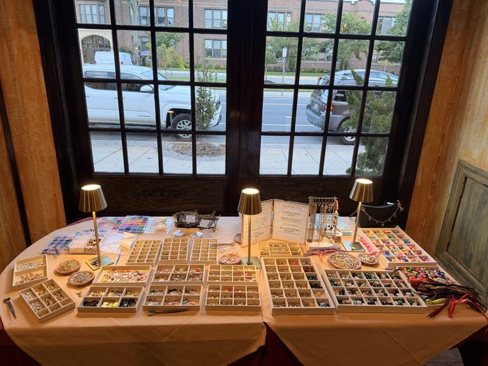 Hoop & Hand charm bar set up at a restaurant event, with trays of charms and beads
