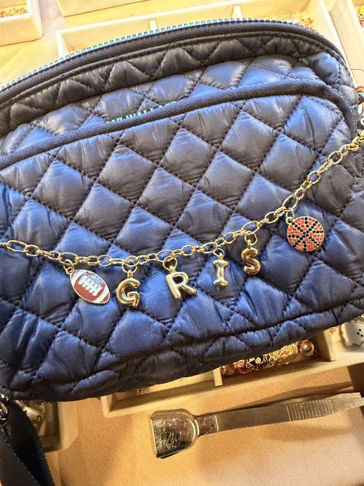 charm chain spelling GRIS on a quilted navy bag