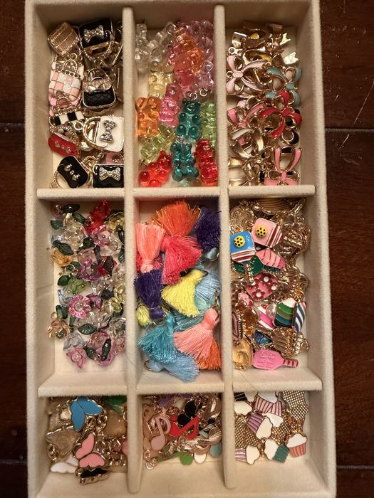 Tray of enamel charms, tassels and beads