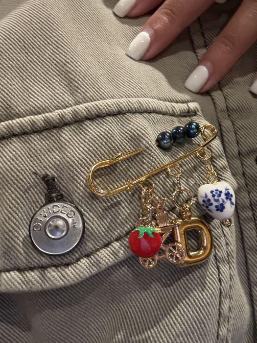 Safety pin brooch with tomato, letter D and porcelain heart charms on a denim jacket