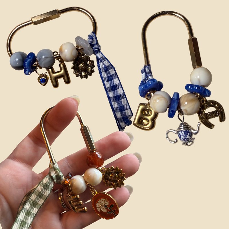 Three carabiner keychains with gingham ribbons, marbled beads, letter charms and sunflower, teapot and horseshoe charms