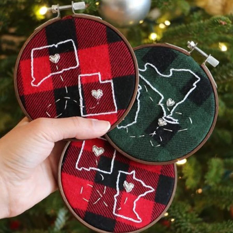 Red and green buffalo check hoop ornaments each stitched with two state outlines joined by a dotted line and hearts
